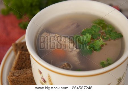 Clear Beef Broth, Bouillon In White Bowl And Vegetables On Wooden Table. Rustic Style.