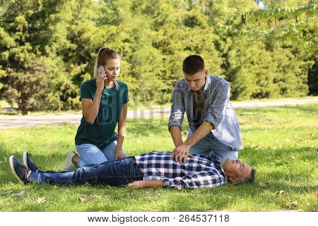 Passersby Helping Unconscious Man Outdoors. First Aid