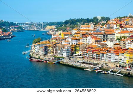 PORTO, PORTUGAL - AUGUST 29, 2018: A view of the Douro River and the old town of Porto, in Portugal, with its characteristic houses of different colors, and the Arrabida bridge in the background