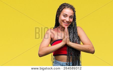 Young braided hair african american with pigmentation blemish birth mark over isolated background praying with hands together asking for forgiveness smiling confident.