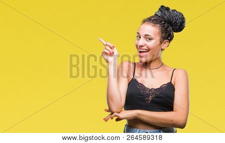 Young braided hair african american with pigmentation blemish birth mark over isolated background with a big smile on face, pointing with hand and finger to the side looking at the camera.