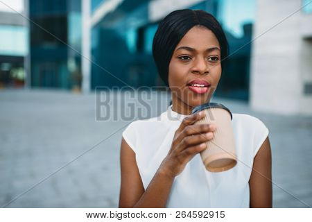 Business girl grinks coffee from cardboard cup