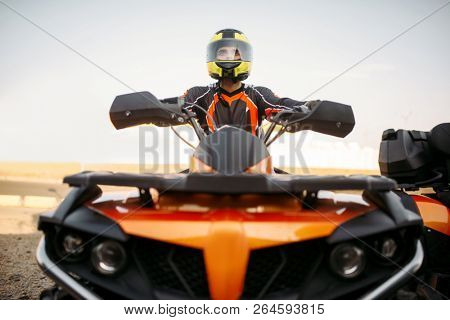 Rider in helmet on quad bike, front view, closeup