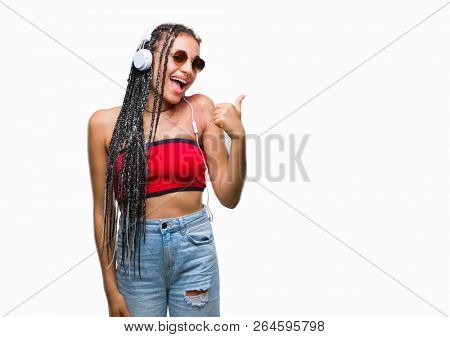 Young braided hair african american with birth mark wearing headphones over isolated background doing happy thumbs up gesture with hand. Approving expression looking at the camera with showing success