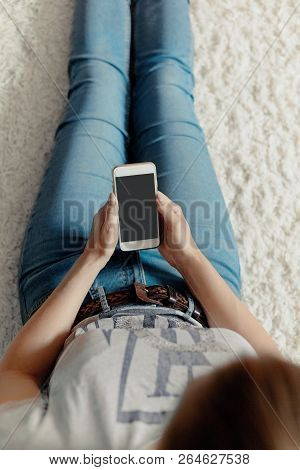 Young Woman Holding Credit Card And Using Phone Sitting On Floor. Payment.  Online Shopping Concept.