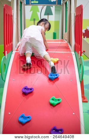 Asian Chinese Little Girl Playing At Mini Rock Climbing Wall At Indoor Playground
