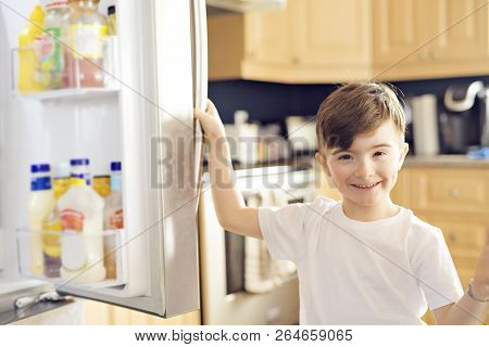 Young White Boy Standing In Front Of Open Refrigerator.