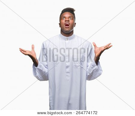 Young arabic african man wearing traditional djellaba over isolated background crazy and mad shouting and yelling with aggressive expression and arms raised. Frustration concept.
