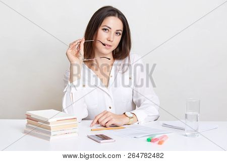 Self Assured Entrepreneur Works In Business Documentation, Keeps Eyewear Near Mouth, Prepares For Bu