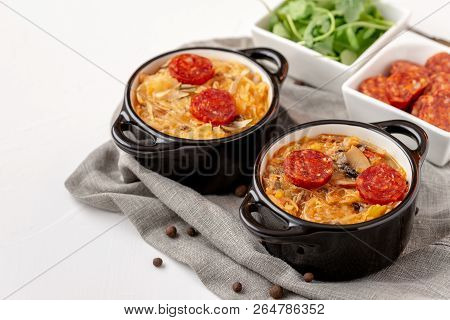 Slovak Christmas Cabbage Soup In Two Small Pots With Sausage On The Top On White Background.