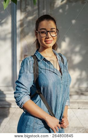 Young Attractive Bespectacled Woman Looking At The Camera And Smiling.