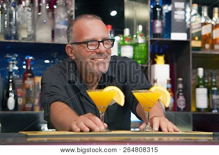 The Barman Gives A Cocktail To The Client Of The Hotel Bar. Fresh Cocktail With Orange. Alcoholic, N