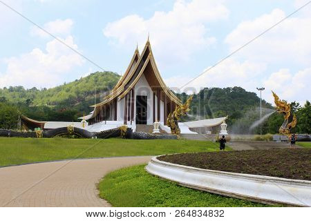 Side Angle Of The White Buddhist Temple With Dragon Fountains And A Pathway At Ban Nong  Thailand