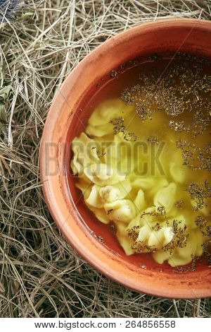 Beautiful Serving Vintage Ceramic Bowl of Homemade Soup with Mini Dumplings on Rustic Background Top View