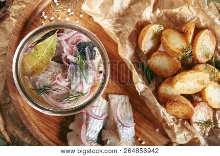 Marinated Herring in Vinegar with Potatoes, Oil, Dill, Onion and Spices on Rustic Background Top View. Beautiful Creative Sea Food Vintage Design of Pickled Fish Fillet with Baked Potato