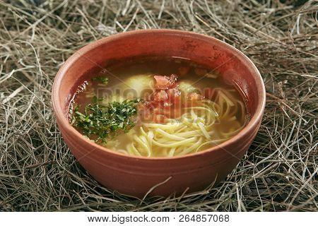 Beautiful Serving Vintage Ceramic Bowl of Homemade Noodle Soup Arishta with Chicken Meatballs. Clear Sturdy Seasoned Broth with Turkey Meat Balls, Egg Spaghetti and Greens on Rustic Background