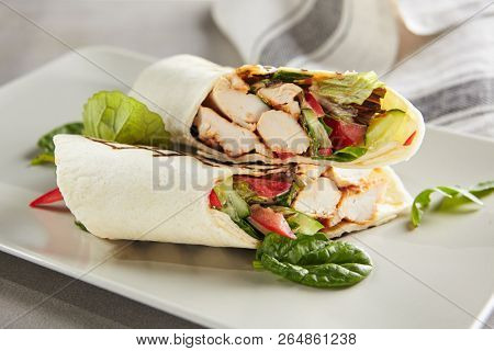 Chicken Shaverma or Doner Kebab with Vegetables on a White Plate Close Up. Rolls of Wheat Tortillas Stuffed with Turkey Fillet Cucumber, Tomato and Greens