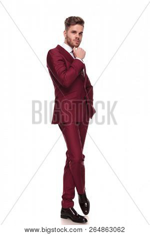 attractive elegant man thinking while standing with legs crossed