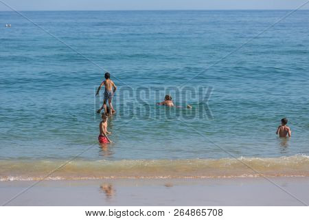 VILA DO BISPO, PORTUGAL - AUGUST 21, 2018: People at the famous beach of Salema in Vila do Bispo. This beach is a part of famous tourist region of Algarve.