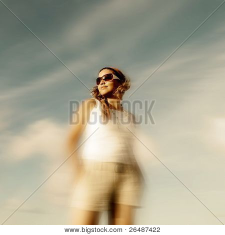 Retrato de jovem usando óculos escuros de pé contra o céu azul de Verão