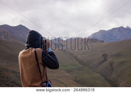 Young Curly Traveler Taking Photo With Camera In Kazbegi. Beautiful View Of Kazbegi In Autumn