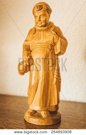 Hand Carved Wooden Monk Figurine On Reflective Wood