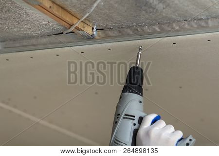 Close-up Of Constructor Worker Hand In Protective Glove With Electrical Cordless Screwdriver Connect
