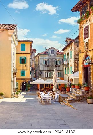 Lovran, Croatia. Central area of ancient old town with vintage buildings and cosy street cafes and restaurants. Sunny summer day. Urban landscape of historical centre.