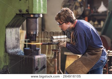 Young Blaksmith Working With Red Hot Metal In A Workshop