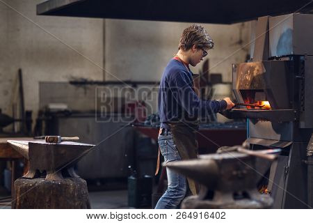 Young Blaksmith Working In A Metalworking Workshop