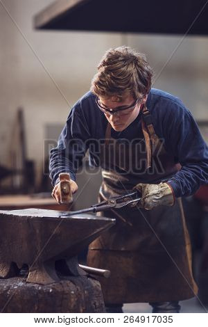Young Blaksmith Working With Hot Metal In A Workshop