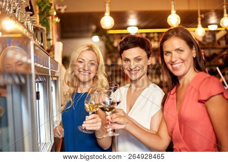 people, alcohol tasting and lifestyle concept - happy women drinking wine and toasting at bar or restaurant
