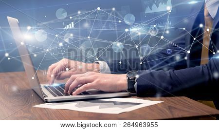 Businessman typing on laptop with linked reports charts grapghs around