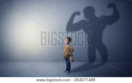 Little waggish boy in an empty room with musclemen shadow behind