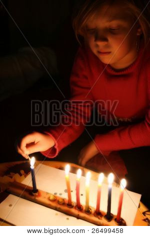A girl lights a candle in the Jewish holiday of Hanukkah