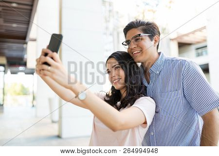 Cute Girlfriend Taking Selfportrait With Boyfriend Using Mobile Phone In Shopping Mall