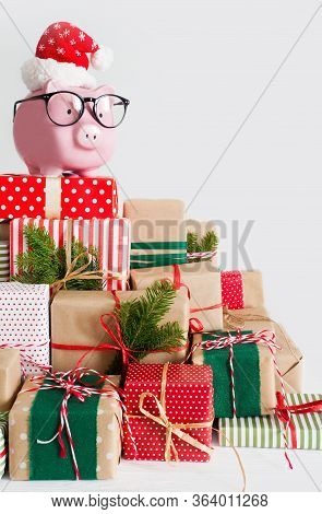 Piggy Bank In Santa Claus Hat. Christmas Gift Boxes. White Background. The Concept Of Saving.