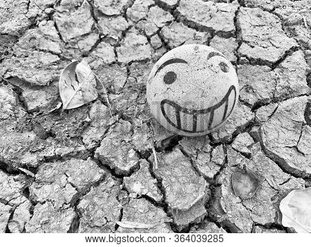 Top View Shot Of Cracked Dry Soil With Smiling Ball And Leaf. Depressive Mood