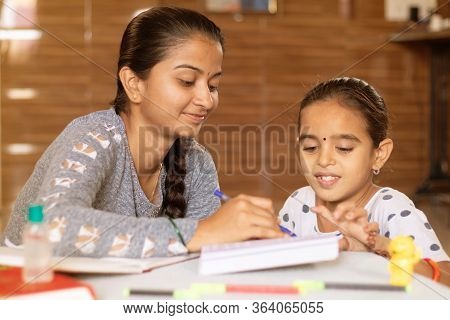 Young Girl Teaching Her Sister At Home - Conept Of Homeschooling During Coronavirus Or Covid-19 Lock