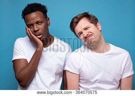 Portrait Of Two Bored Young Men, Isolated Blue Background