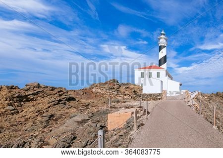 View Of The Lighthouse (faro De Favaritx) In Sunny Weather With Beautiful Clouds In The Sky On The I