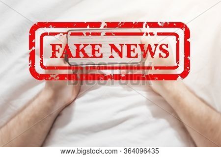 Fake News Infodemics During Covid-19 Pandemic Concept. Man Hands Holding Mobile Phone Reading Global