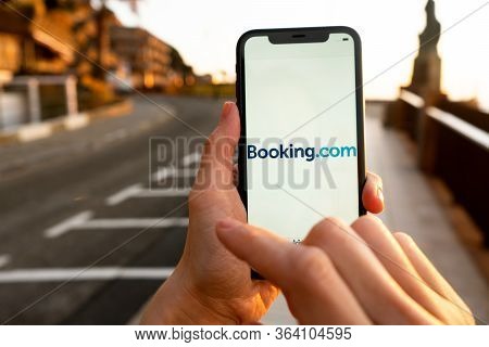 Hands holding iPhone 11 with an app of booking.com service. Holidays and vacation concept. A woman f