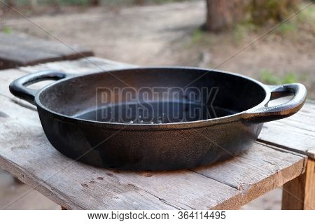 Iron Empty Pan On Wooden Background Table. Vintage Cast Pan