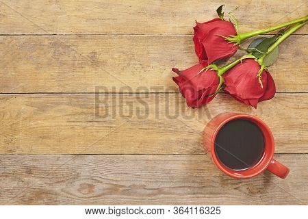 Red Rosesand Cup Of Coffee On Wooden Background With Copy Space. Top View