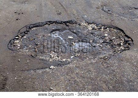 A Pit In The Asphalt With Mud At The Bottom After The Water Has Dried