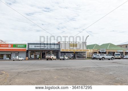 Harrismith, South Africa - March 16, 2020:  A Street Scene, With Businesses, Vehicles And A Car Guar