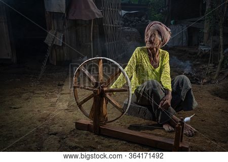 Ubud, Gianyar, Bali, Indonesia - June 28, 2019 : Old Balinese Woman With Her Spinning Wheel In A Sma