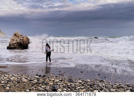 Unrecognized Person Enjoying The Stormy Seascape With Windy Waves. Rock Of Aphrodite Birthplace, Pet