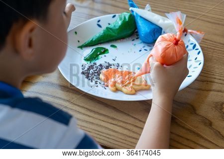 Closeup Hand Of Boy Doing The Bakery Workshop By Squeezing The Liquid Sugar On The Cookie